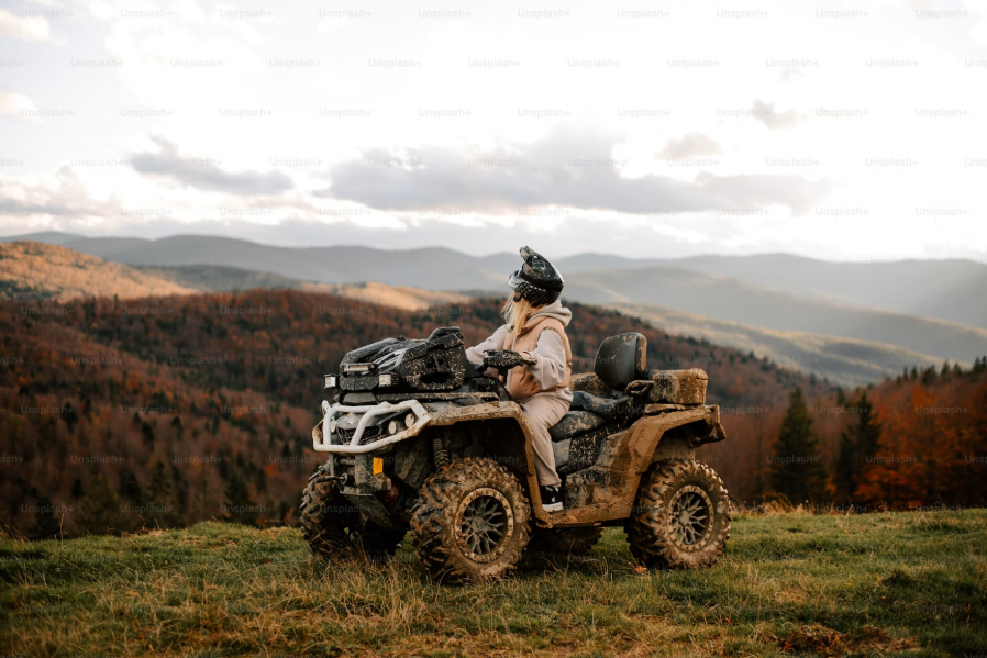 Жена с ATV сред планински пейзаж и есенна гора.